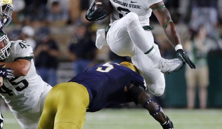FILE - In this Sept. 17, 2016, file photo, Michigan State running back LJ Scott (3) carries the ball and hurdles Notre Dame linebacker Nyles Morgan (5) during the first half of an NCAA college football game in South Bend, Ind. No. 13 Notre Dame has adjusted well to a new defensive scheme under coordinator Mike Elko. It will face a big test on Saturday night against No. 11 Southern California, which is led by quarterback Sam Darnold. (AP Photo/Charles Rex Arbogast, File)