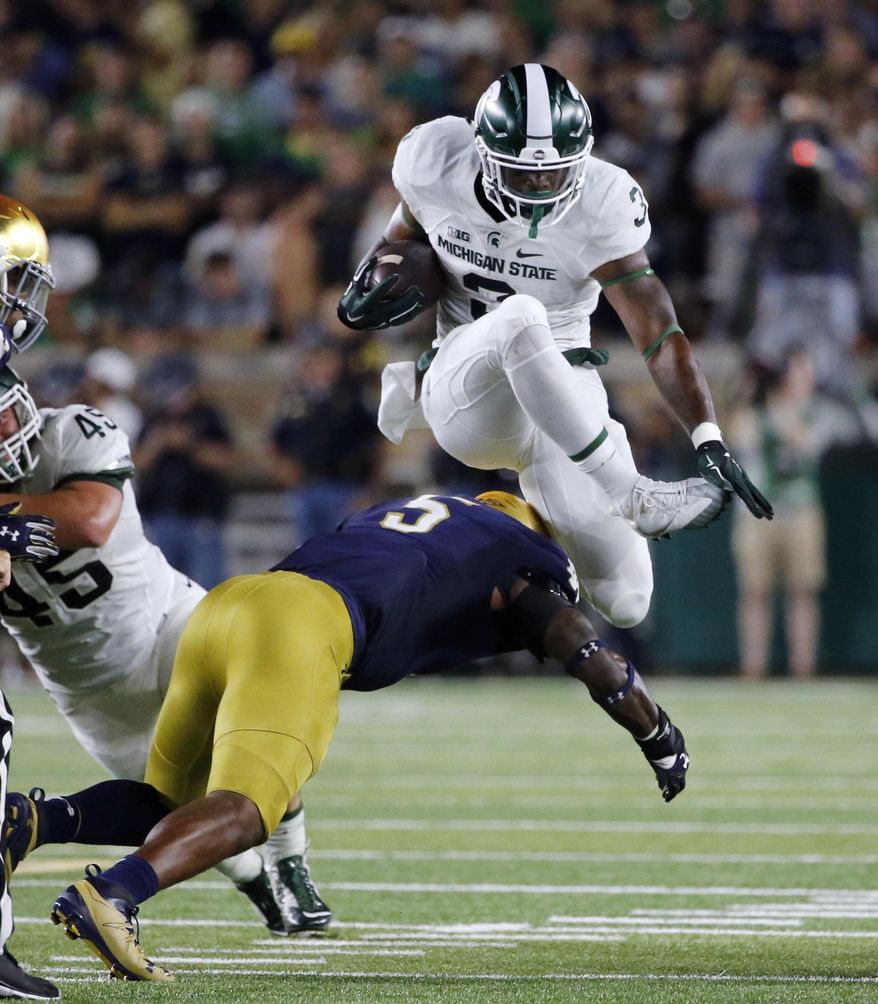 FILE - In this Sept. 17, 2016, file photo, Michigan State running back LJ Scott (3) carries the ball and hurdles Notre Dame linebacker Nyles Morgan (5) during the first half of an NCAA college football game in South Bend, Ind. No. 13 Notre Dame has adjusted well to a new defensive scheme under coordinator Mike Elko. It will face a big test on Saturday night against No. 11 Southern California, which is led by quarterback Sam Darnold. (AP Photo/Charles Rex Arbogast, File)