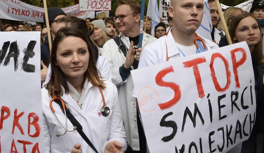 Young doctors rally in front of the prime minister's office to demand increases of their low earnings and more spending on the chronically strapped and inefficient health care, in Warsaw, Poland, Saturday, Oct. 14, 2017. The placard right reads: Stop dying in queues. (AP Photo/Alik Keplicz)