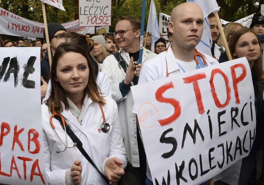 Young doctors rally in front of the prime minister's office to demand increases of their low earnings and more spending on the chronically strapped and inefficient health care, in Warsaw, Poland, Saturday, Oct. 14, 2017. The placard right reads: Stop dying in queues. (AP Photo/Alik Keplicz)