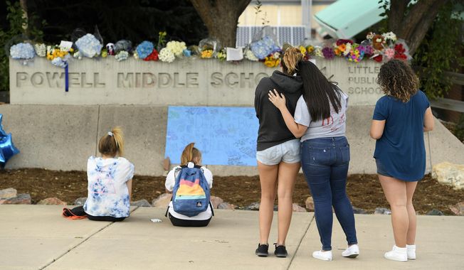 This photo taken Aug. 31, 2017, file shows students pausing to reflect at a memorial at Powell Middle School set up for a student who recently took their own life in Littleton, Colo. The young student took his own life at Twain Elementary School. Two young students from Littleton Public Schools have taken their own lives over a two-day period concerning parents, students and schools. (Helen H. Richardson/The Denver Post via AP) ** FILE **