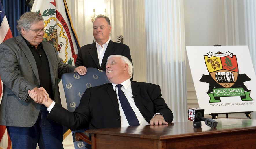 West Virginia Gov. Jim Justice, center, shakes hands with West Virginia Great Barrel Co. managing partners Tom Crabtree, left, and Philip Cornett following the announcement Thursday, Oct. 19, 2017, in Charleston W.Va., that a barrel-making facility will be constructed in White Sulphur Springs. The company that makes whiskey barrels out of white oak wood has been born from efforts to rebuild a devastated West Virginia community following deadly floods. (Chris Dorst/Charleston Gazette-Mail via AP)