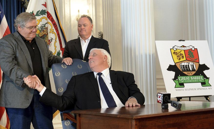 West Virginia Gov. Jim Justice, center, shakes hands with West Virginia Great Barrel Co. managing partners Tom Crabtree, left, and Philip Cornett following the announcement Thursday, Oct. 19, 2017, in Charleston W.Va., that a barrel-making facility will be constructed in White Sulphur Springs. The company that makes whiskey barrels out of white oak wood has been born from efforts to rebuild a devastated West Virginia community following deadly floods. (Chris Dorst/Charleston Gazette-Mail via AP)