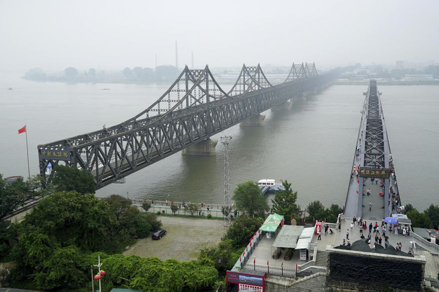 FILE - In this Sept. 9, 2017, file photo, visitors walk across the Yalu River Broken Bridge, right, next to the Friendship Bridge connecting China and North Korea in Dandong in northeastern China's Liaoning province. China and North Korea share a long border, history and ideology, but the notion that Beijing can use its influence to force Pyongyang to abandon its nuclear bombs runs against a complicated reality. Their relationship is less about friendship or political bonds than a deep and mutually uneasy dependency. (AP Photo/Emily Wang, File)