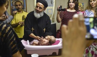 In this July 15, 2017 photo, Father Girigis Ramandious performs a &amp;quot;baby shower&amp;quot; for 40-day-old Heaven Khalil at St. Mary&#39;s Catholic Church in York, Pa. Coptic baby boys are baptized when 40 days old while baby girls are baptized when 80 days old. About 60 Egyptian Coptic Christian families have moved to York County in recent years to escape religious persecution in Egypt, where Copts face systematic discrimination and experience attacks by Islamic extremists.   (Chris Dunn/York Daily Record via AP)