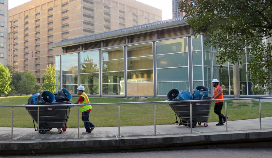 In this Oct. 19, 2017 photo, two workers remove equipment that is being used to clean up and dry the $13 million Harris County Jury Assembly Building in Houston, which is located underground and was flooded during torrential rainfall after Hurricane Harvey made landfall. Harris County's criminal courthouse, located across the street, also suffered heavy damage during Harvey and will be closed for up to a year. (AP Photo/Juan Lozano)