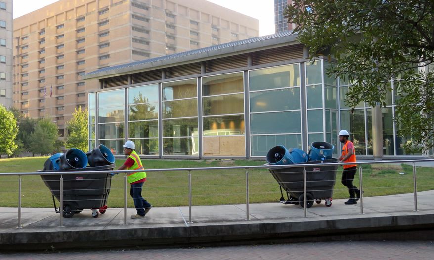 In this Oct. 19, 2017 photo, two workers remove equipment that is being used to clean up and dry the $13 million Harris County Jury Assembly Building in Houston, which is located underground and was flooded during torrential rainfall after Hurricane Harvey made landfall. Harris County's criminal courthouse, located across the street, also suffered heavy damage during Harvey and will be closed for up to a year. (AP Photo/Juan Lozano)