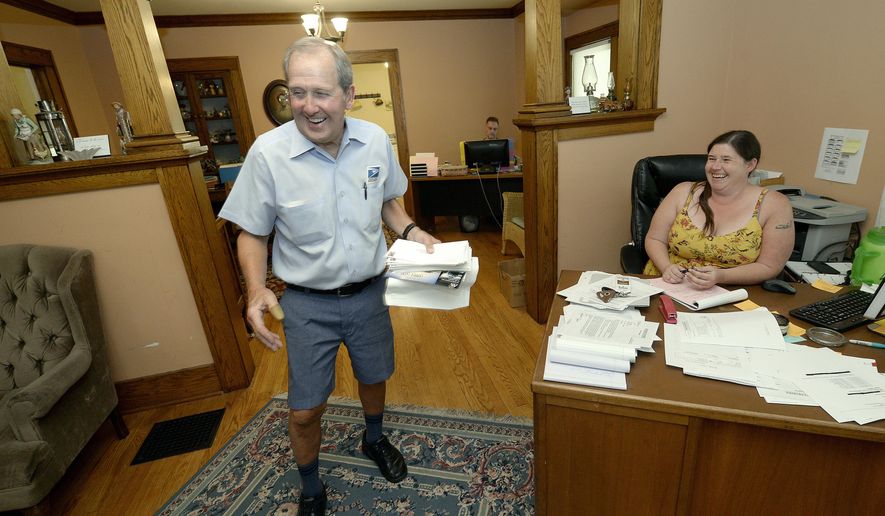 In this June 15, 2017 photos, postal carrier Larry Schultz leaves Ally Stewart laughing as he delivered mail to a law office on his route near the capitol in Lincoln, Neb. (Eric Gregory/The Journal-Star via AP)