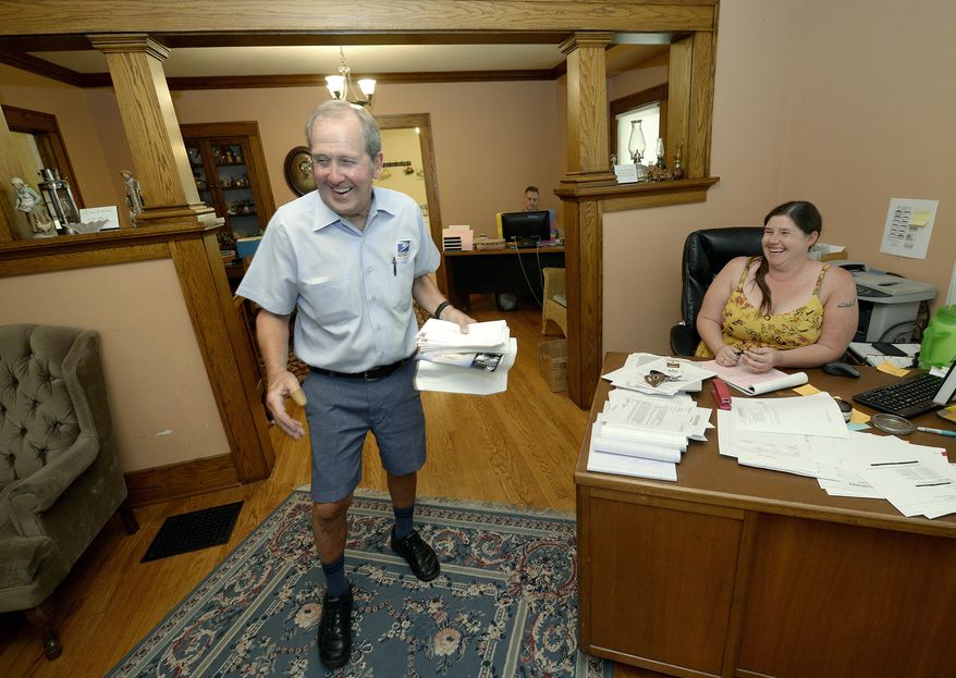 In this June 15, 2017 photos, postal carrier Larry Schultz leaves Ally Stewart laughing as he delivered mail to a law office on his route near the capitol in Lincoln, Neb. (Eric Gregory/The Journal-Star via AP)