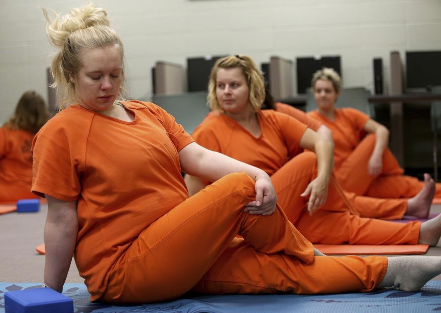 Scott County inmate Melinda Heyvaert and other inmates get into a position during a yoga class held at the Scott County Jail in Davenport, Iowa, on Wednesday, Oct. 11, 2017. The class is taught by volunteer Joan Marttila. (John Schultz/Quad City Times via AP)