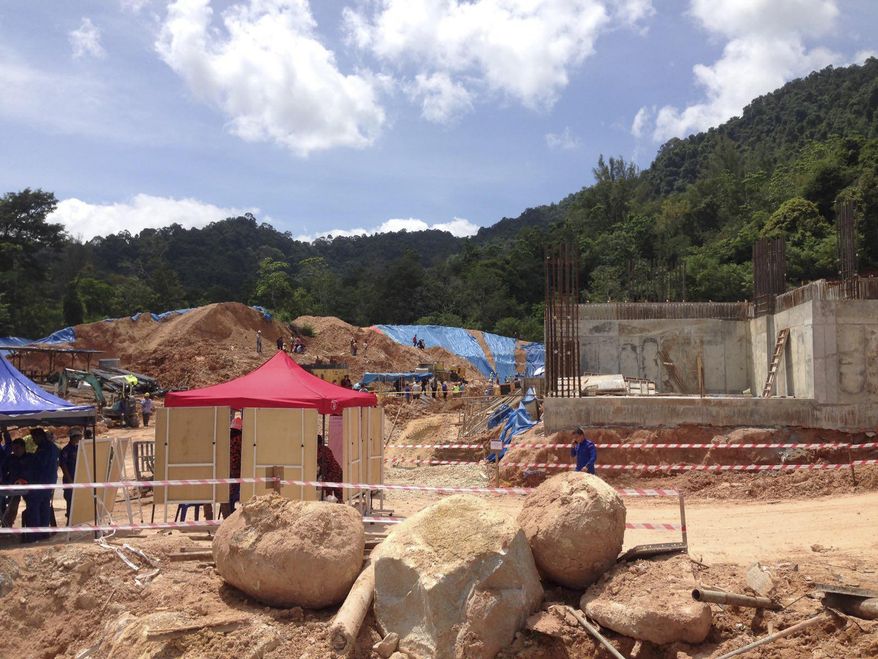 A rescue operation is conducted at a construction site after a landslide in Penang, Malaysia, Saturday, Oct. 21, 2017. Fire and rescue official Mohamad Rizuan Ramli said a 10-meter high hill slope crashed down at the construction site early Saturday. (AP Photo/Peter Ewe)