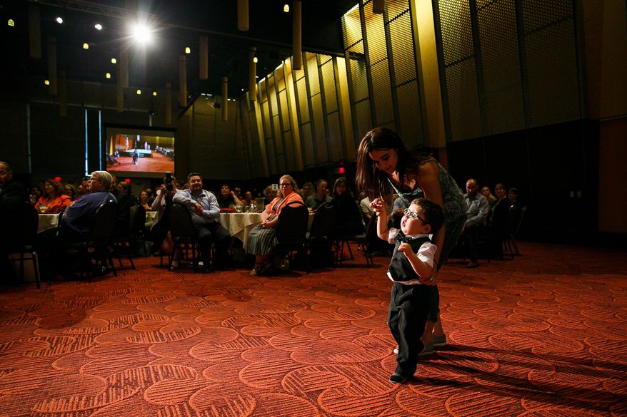 In a Tuesday, Sept. 12, 2017 photo, Joey Shewey walks with the help of caregiver Victoria Gidenko at the SKEF luncheon at the Salem Convention Center. Shewey, who uses a walker for assistance, walked in the Awesome 3000 with the encouragement of SKEF employee Hilary Brik-Morris, who was honored at the luncheon.  (Molly J. Smith/Statesman-Journal via AP)