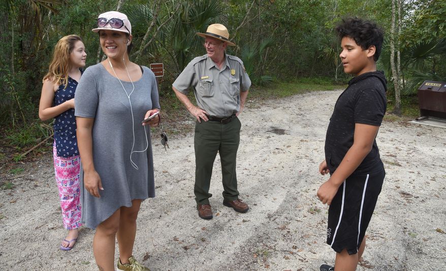 In this Oct. 4, 2017 photo, Craig Morris, center, a National Park Ranger at Fort Caroline National Memorial, meets a family from Jupiter, Fla., who stopped to visit the fort at Robert Gallegos-Duran's, right, insistence as they passed through town in Jacksonville, Fla. (Bruce Lipsky/The Florida Times-Union via AP)