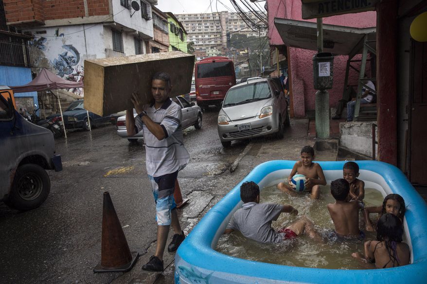 Children play in an inflatable swimming pool in the working class 23 de Enero neighborhood as it rains lightly in Caracas, Venezuela, Saturday, Oct. 21, 2017. (AP Photo/Rodrigo Abd)