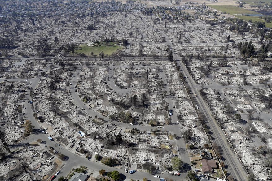 FILE - In this Oct. 14, 2017 file photo, an aerial view shows the devastation of the Coffey Park neighborhood after a wildfire swept through it in Santa Rosa, Calif. CalFire spokesman Daniel Berlant said Monday, Oct. 23, 2017, the estimate of homes and structures destroyed was boosted from 6,900 late last week to 8,400 as officials neared completion of their damage assessment. (AP Photo/Marcio Jose Sanchez, File)