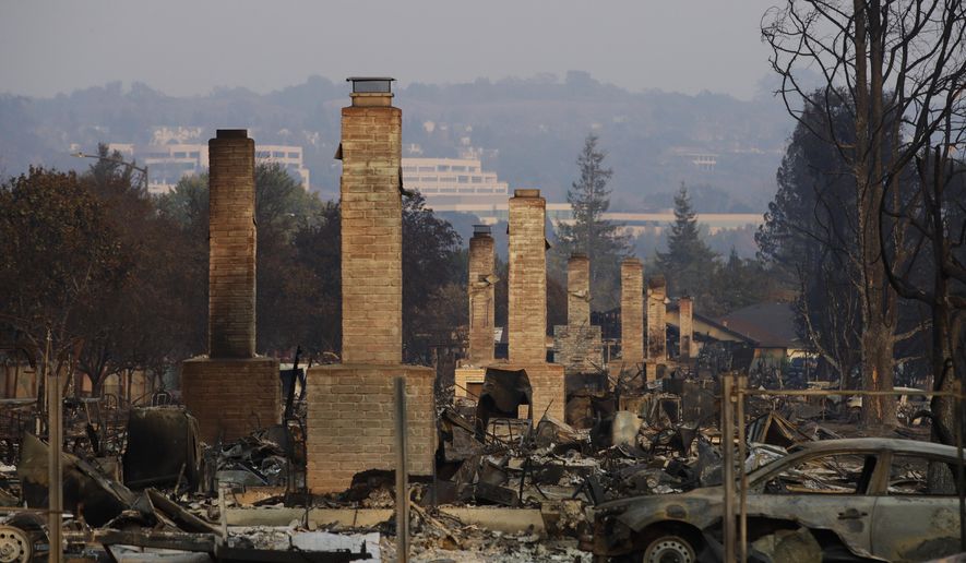 FILE - In this Oct. 13, 2017 file photo, a row of chimneys stand in a neighborhood devastated by a wildfire near Santa Rosa, Calif. CalFire spokesman Daniel Berlant said Monday, Oct. 23, 2017, the estimate of homes and structures destroyed was boosted from 6,900 late last week to 8,400 as officials neared completion of their damage assessment. (AP Photo/Jae C. Hong, File)