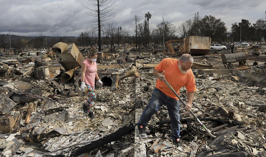 Sarah Boryszewski is helped by her father Gerald Peete as they dig for belongings in the remains of Boryszewski's home in Coffey Park, Friday Oct. 20, 2017 in Santa Rosa, Calif. Northern California residents who fled a wildfire in the dead of night with only minutes to spare returned to their neighborhoods Friday for the first time in nearly two weeks to see if anything was standing. (Kent Porter/The Press Democrat via AP)