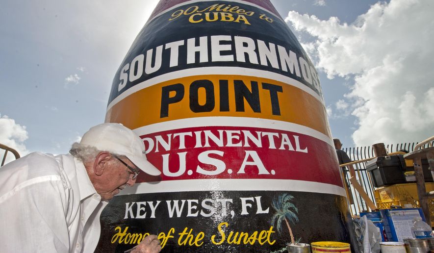 In this photo provided by the Florida Keys News Bureau, artist Danny Acosta completes lettering the Southernmost Point in the Continental U.S.A. marker Monday, Oct. 23, 2017, in Key West, Fla. One of the most-photographed tourism icons in the Florida Keys was pummeled by Hurricane Irma on Sept. 10, stripping most of the paint and a large chunk of stucco. (Rob O'Neal/Florida Keys News Bureau via AP)