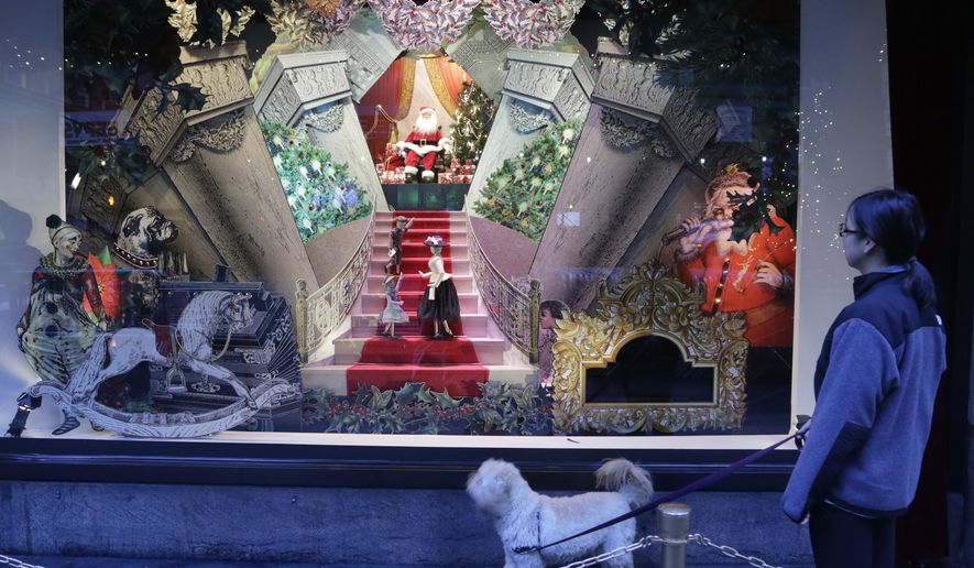 FILE - In this Nov. 18, 2013, file photo, a woman walks her dog past a vintage Santa Claus holiday window display at Lord & Taylor department store in New York. A real estate startup called WeWork Cos. is announcing a deal to buy Lord & Taylor’s storied flagship in Manhattan for $850 million. The transaction, announced Tuesday, Oct. 24, 2017, is part of an overall plan by Lord & Taylor’s parent Hudson’s Bay Co. to pare down its debt and reinvigorate the chain. (AP Photo/Mark Lennihan, File)