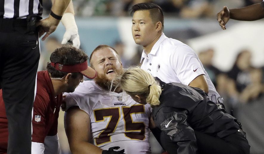 In this Monday, Oct. 23, 2017, file photo, trainers look examine Washington Redskins offensive guard Brandon Scherff (75) during the second half of an NFL football game against the Philadelphia Eagles in Philadelphia. The banged-up Redskins got some good news about Scherff’s knee injury with coach Jay Gruden saying there’s a chance Scherff can play Sunday against the Dallas Cowboys. Scherff sprained the MCL in his left knee and hurt his lower back, one of several Redskins injuries from a 34-24 loss at the Philadelphia Eagles on Monday night. (AP Photo/Matt Rourke, File)  **FILE**