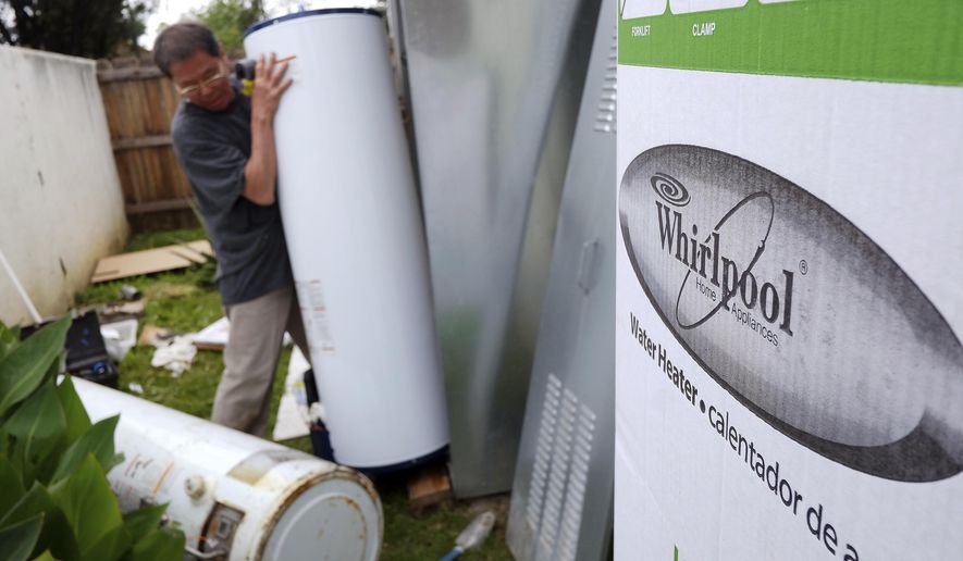 FILE - In this Sunday, March 22, 2015, file photo, a repairman installs a Whirlpool water heater at a home in Los Angeles. Sears will no longer sell Whirlpool appliances, ending a business partnership that dates make more than 100 years. (AP Photo/Richard Vogel, File)
