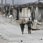 In this July 26, 2017 file photo, U.S.-backed Syrian Democratic Forces fighters walk past destroyed shops where they fight against Islamic State group militants, on the eastern side of Raqqa, Syria. (AP Photo/Hussein Malla, File)