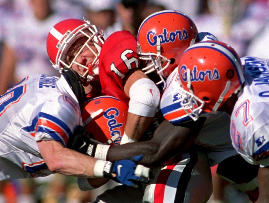 FILE - In this Oct. 28, 1995, file photo, Georgia's Kirby Smart (16) is tackled by Florida's Sam McCorkle (left), Demetric Jackson (27) and Kavin Walton, center, during the first quarter of an NCAA college football game at Sanford Stadium in Athens, Ga. There have been a dozen upsets in the last 33 meetings between Georgia and Florida, making "The World's Largest Outdoor Cocktail Party" one of college football's most unpredictable rivalries. (AP Photo/Dave Martin, File)