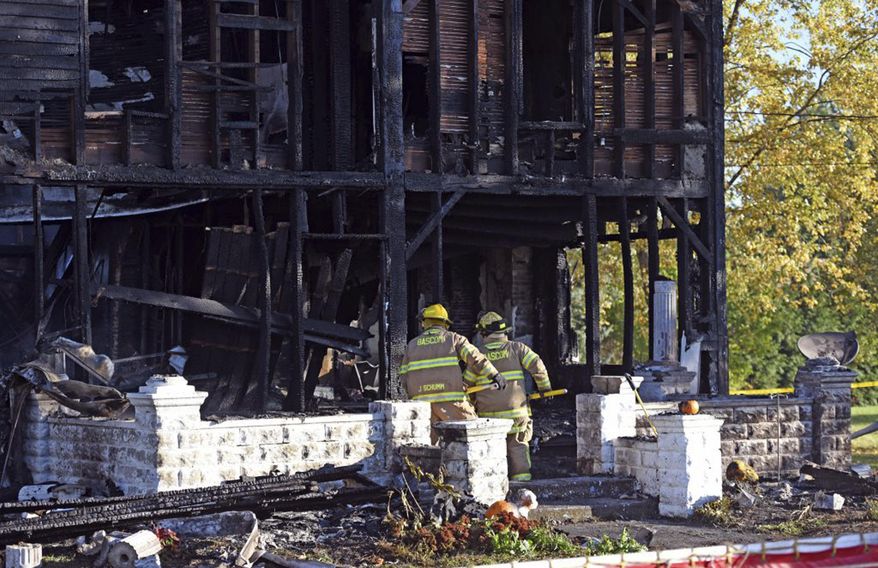 Investigators look through rubble after a farmhouse fire Thursday, Oct. 26, 2017 near Fostoria, Ohio. Investigators have found the bodies of multiple people who died in the fire. Authorities say they believe five people had been living in the house, including some children. A Seneca County spokesman says arriving firefighters were unable to get inside the burning house because the flames and smoke were too intense. (Randy Roberts/The Review Times via AP)