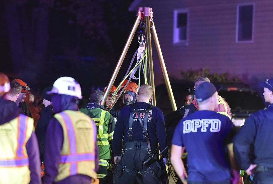 First responders work around a manhole to rescue a man who is trapped underground in Streamwood, Ill., Wednesday, Oct. 25, 2017. The Daily Herald reports firefighters worked roughly four hours Wednesday night to pull a worker out of a manhole. Firefighters did not realize he was dead until after he was pulled from the manhole. (John Starks/Daily Herald via AP)