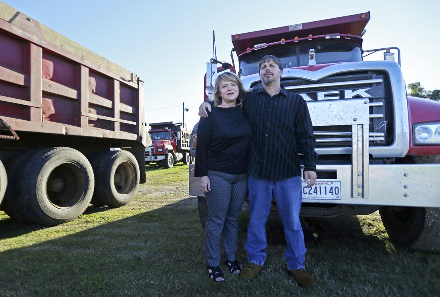 Chad Jarreau poses with his wife Penny Jarreau in front of one of their dump trucks in Cutt Off, La., Tuesday, Oct. 24, 2017. Jarreau had land taken from him by the local bayou districts. They are asking the Supreme Court for help after the local flood control district took some of his land and part of his livelihood, paying him a pittance. (AP Photo/Gerald Herbert)
