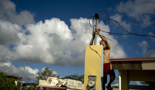 In this Friday, Oct. 13, 2017 file photo, a resident tries to connect electrical lines downed by Hurricane Maria in preparation for when electricity is restored in Toa Baja, Puerto Rico.  (AP Photo/Ramon Espinosa) **FILE**