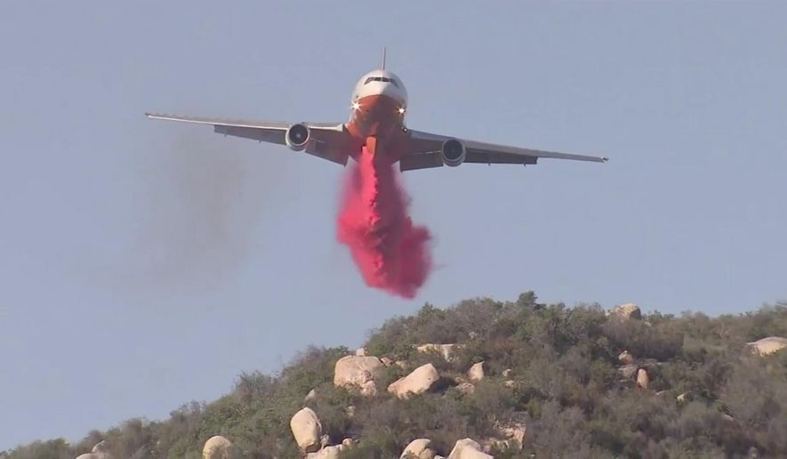 In this Friday, Oct. 27, 2017, still image taken from a video provided by KABC-TV, an air tanker drops fire retardant on a wildfire in Wildomar, Calif. The fire began early Thursday afternoon in the Wildomar Off-Highway Vehicle Area in the Cleveland National Forest, about 70 miles (112 kilometers) southeast of Los Angeles. (KABC-TV via AP)