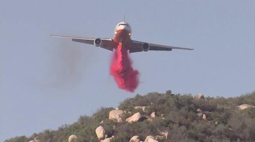 In this Friday, Oct. 27, 2017, still image taken from a video provided by KABC-TV, an air tanker drops fire retardant on a wildfire in Wildomar, Calif. The fire began early Thursday afternoon in the Wildomar Off-Highway Vehicle Area in the Cleveland National Forest, about 70 miles (112 kilometers) southeast of Los Angeles. (KABC-TV via AP)