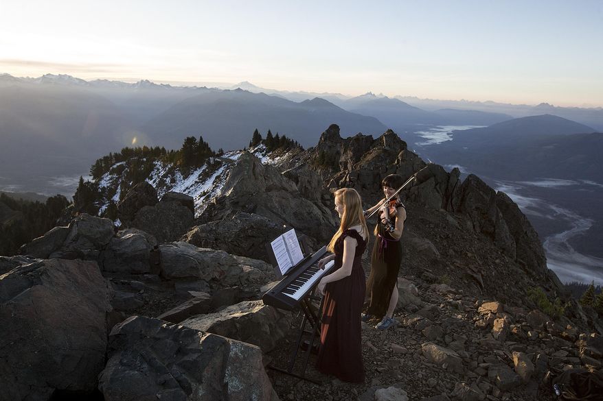 Rose Freeman, center, and Anastasia Allison play atop Sauk Mountain near Concrete, Wash. on Thursday, Oct. 5, 2017. The pair play violin and piano together at sunrise across the Cascades under the name, The Musical Mountaineers. (Ian Terry/The Everett Herald via AP)