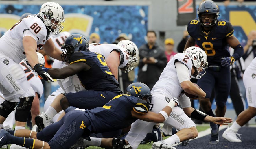 Oklahoma State quarterback Mason Rudolph (2) runs the ball for a touchdown as West Virginia safety Kenny Robinson (2) tries to stop him during the first half of an NCAA college football game, Saturday, Oct. 28, 2017, in Morgantown, W.Va. (AP Photo/Raymond Thompson)