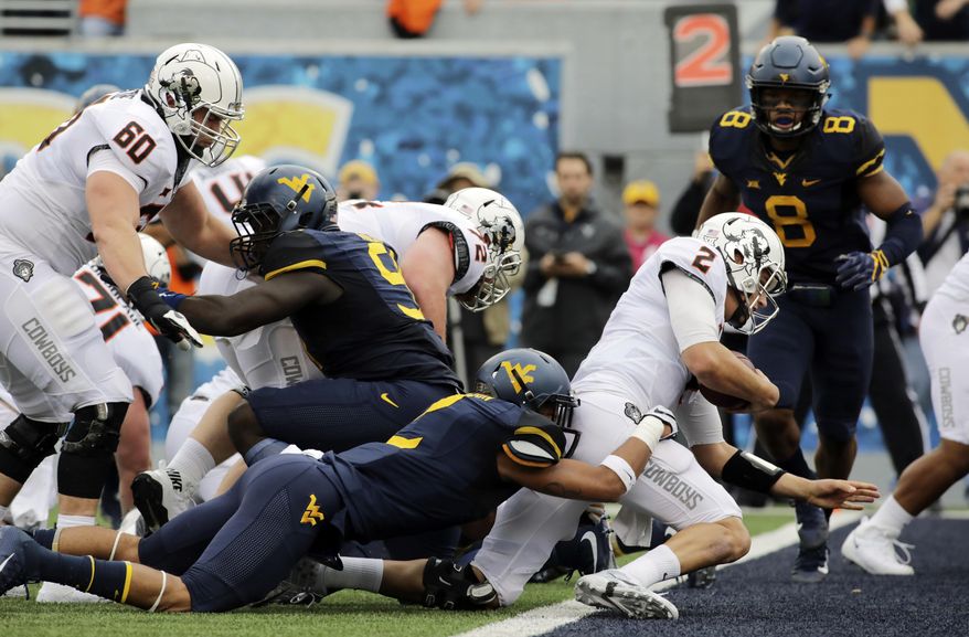 Oklahoma State quarterback Mason Rudolph (2) runs the ball for a touchdown as West Virginia safety Kenny Robinson (2) tries to stop him during the first half of an NCAA college football game, Saturday, Oct. 28, 2017, in Morgantown, W.Va. (AP Photo/Raymond Thompson)