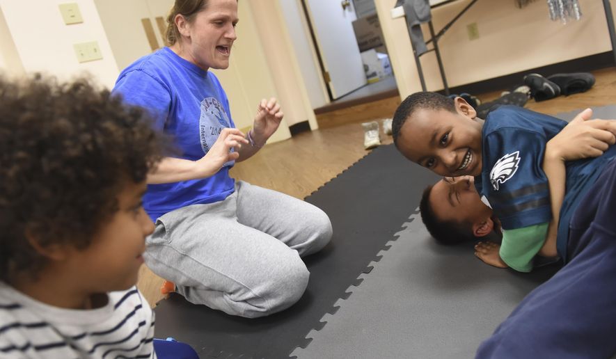 In this Monday, Oct. 23, 2017 photo, Melissa Resek, second from left, cheers as 6-year-old Elijah Mam, right top, wrestles with her son, Joey, 8, during "Tribe Youth Group" at Trinity Lutheran Church in Steeltonm Pa. According to seminary intern David Tringali, the group is a faith formation in the form of a wrestling club. "It comes from this idea that we all wrestle with our faith constantly," said Tringali. (Jason Plotkin/York Daily Record via AP)