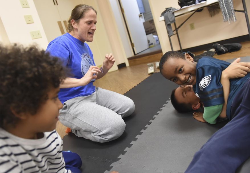 In this Monday, Oct. 23, 2017 photo, Melissa Resek, second from left, cheers as 6-year-old Elijah Mam, right top, wrestles with her son, Joey, 8, during "Tribe Youth Group" at Trinity Lutheran Church in Steeltonm Pa. According to seminary intern David Tringali, the group is a faith formation in the form of a wrestling club. "It comes from this idea that we all wrestle with our faith constantly," said Tringali. (Jason Plotkin/York Daily Record via AP)