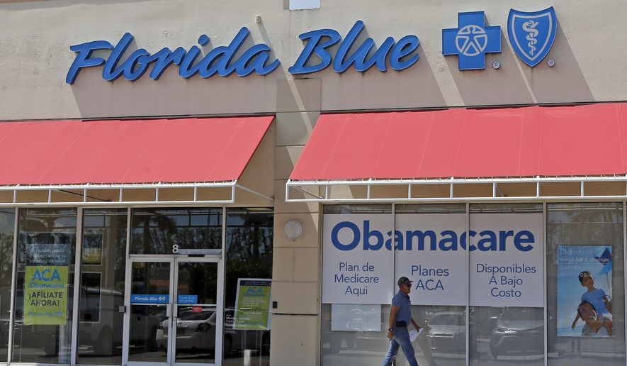 FILE - In this Thursday, July 27, 2017, file photo, a person walks by a health care insurance office in Hialeah, Fla. Health insurance shoppers will face a new deadline, rising prices and fewer options for help in many markets when the Affordable Care Act’s main enrollment window for 2018 coverage opens Wednesday, Nov. 1. Insurance experts say those who need insurance should avoid waiting to do last-minute shopping. (AP Photo/Alan Diaz, File)