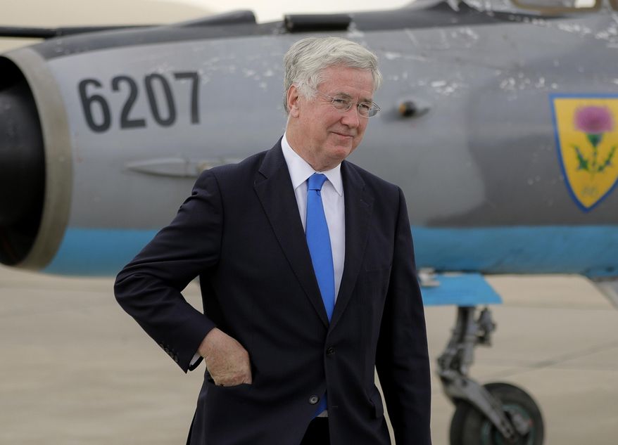 FILE - A Wednesday, June 14, 2017 file photo of Britain's Defense Minister Michael Fallon walking next to a Soviet era built MIG21 jet fighter at the Mihail Kogalniceanu air base, Romania. The UK government said Wednesday, Nov. 1, 2017 that Defense Secretary Michael Fallon has resigned after allegations of inappropriate behavior. (AP Photo/Vadim Ghirda, File)