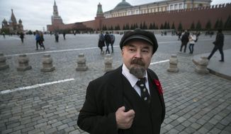 In this photo taken on Wednesday, Oct. 11, 2017, Sergei Soloviev, who impersonates Soviet founder Vladimir Lenin, waits for tourists to pose for photos in Red Square in Moscow, Russia. Visitors are forbidden to photograph Vladimir Lenin’s mummified body in the mausoleum on Red Square - but nearby, Sergei Soloviev is happy to offer an alternative. (AP Photo/Pavel Golovkin)