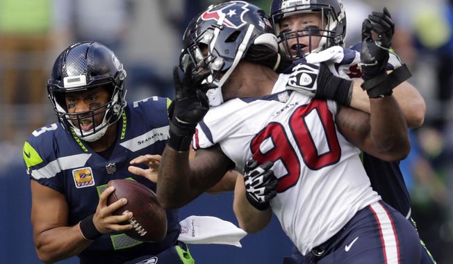 Seattle Seahawks quarterback Russell Wilson, left, keeps the ball as Seattle Seahawks offensive guard Ethan Pocic, right, tries to block Houston Texans outside linebacker Jadeveon Clowney (90) in the second half of an NFL football game, Sunday, Oct. 29, 2017, in Seattle. (AP Photo/Stephen Brashear)