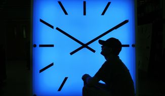 In this Oct. 30, 2008, file photo, Electric Time Company employee Dan Lamoore adjusts the color on a 67-inch square LED color-changing clock at the plant in Medfield, Mass. (AP Photo/Elise Amendola, File)
