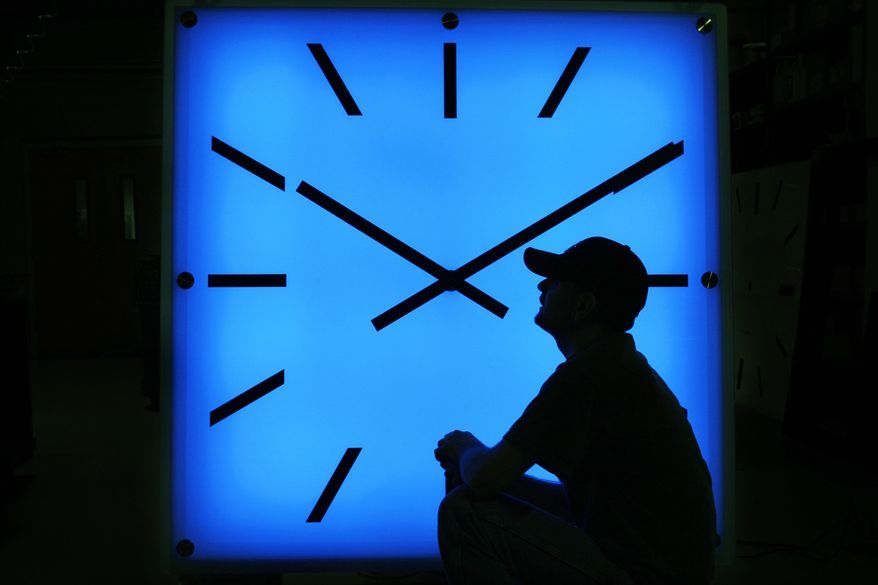 In this Oct. 30, 2008, file photo, Electric Time Company employee Dan Lamoore adjusts the color on a 67-inch square LED color-changing clock at the plant in Medfield, Mass. (AP Photo/Elise Amendola, File)