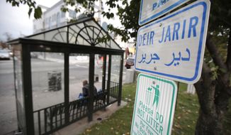 In a photo taken Wednesday, Nov. 1, 2017, Arabic writing is seen on a sign near a bus stop along Main Street in Paterson, N.J. The North Jersey town, which is home to a large Muslim community, has drawn attention in the wake of an attack in Manhattan, where a Paterson resident drove a pick-up truck onto a bike path, killing several people and injuring others. (AP Photo/Julio Cortez)