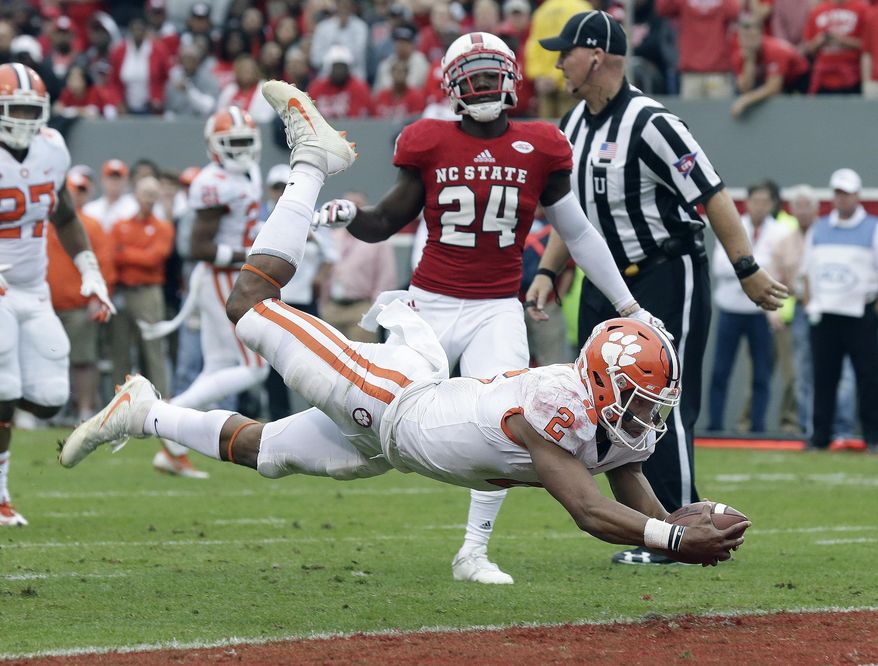 Clemson quarterback Kelly Bryant (2) dives into the end zone for a touchdown while North Carolina State's Shawn Boone (24) looks on during the first half of an NCAA college football game in Raleigh, N.C., Saturday, Nov. 4, 2017. (AP Photo/Gerry Broome)