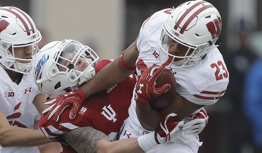 Wisconsin running back Jonathan Taylor (23) runs out of the tackle of Indiana's Chase Dutra (30) during the first half of an NCAA college football game, Nov. 4, 2017, in Bloomington, Ind. (AP Photo/Darron Cummings)