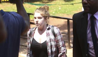 U.S. Citizen Martha O&#39; Donovan appears at the Harare Magistrates court escorted by a plain clothes police officer shielding her face in Harare, Saturday, November, 4, 2017. Police arrested and charged Donavan with subversion for allegedly insulting President Robert Mugabe on Twitter as a &amp;quot;sick man,&amp;quot; lawyers said Friday. The offense carries up to 20 years in prison. (AP Photo/Tsvangirayi Mukwazhi)