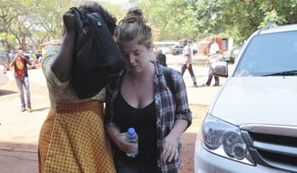 U.S. Citizen Martha O&#39; Donovan, right, appears at the Harare Magistrates court escorted by a plain clothes police officer shielding her face in Harare, Saturday, November, 4, 2017. Police arrested and charged Donavan with subversion for allegedly insulting President Robert Mugabe on Twitter as a &amp;quot;sick man,&amp;quot; lawyers said Friday. The offense carries up to 20 years in prison. (AP Photo/Tsvangirayi Mukwazhi)