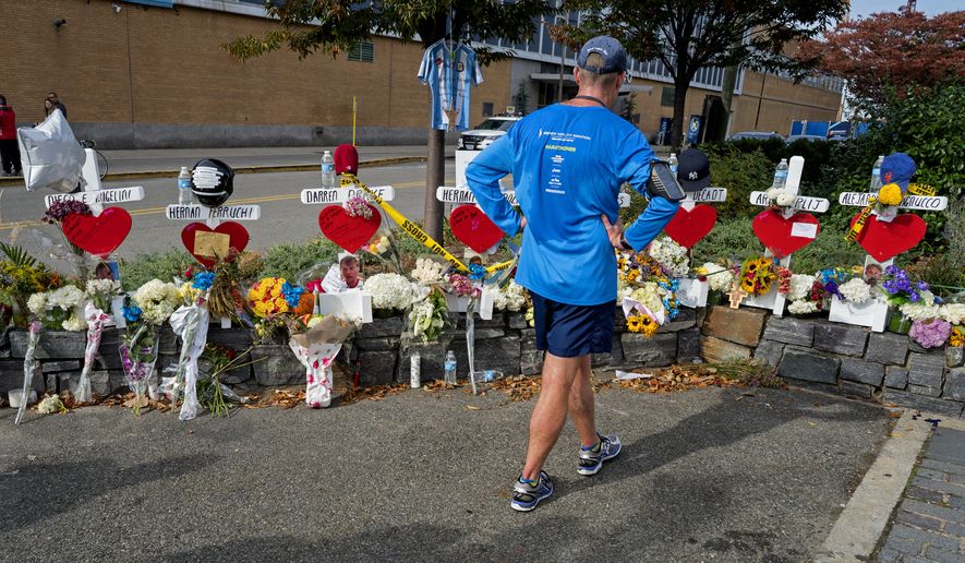 CORRECTS TO HOUSTON NOT CHAMBERS STREET A passerby pauses at a makeshift memorial near a bike path that honors victims of an attack who were stuck and killed by a rental truck driven by indicted suspect Sayfullo Saipov last Tuesday, at Houston and West Streets in New York, Saturday, Nov. 4, 2017. Saipov is accused of using the rental truck to mow down pedestrians and cyclists along the busy bike path. (AP Photo/Craig Ruttle)